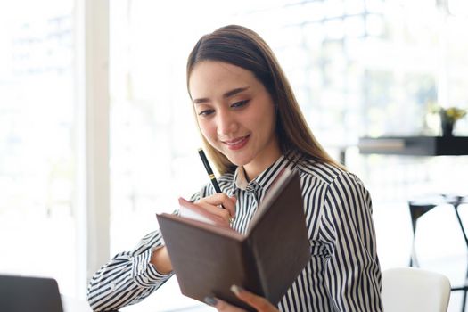 Business woman looking at something in notebook at office, account or saving money or insurance concept.