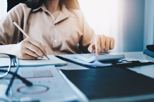 Young economists, accountants or financiers and investors are reviewing budget documents and using notebooks and calculators to study the impact and risk assessment of corporate investment management