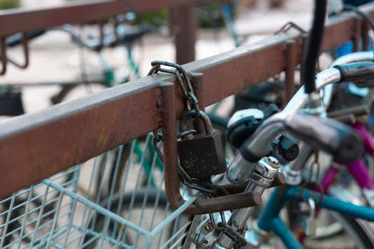 Bicycle chained to a parking. Lock and chain on bicycle handlebar . Lock a bicycle with chain and on bicycle parking.