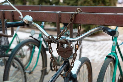 Bicycle chained to a parking. Lock and chain on bicycle handlebar . Lock a bicycle with chain and on bicycle parking.