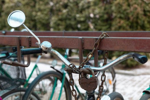 Bicycle chained to a parking. Lock and chain on bicycle handlebar . Lock a bicycle with chain and on bicycle parking.
