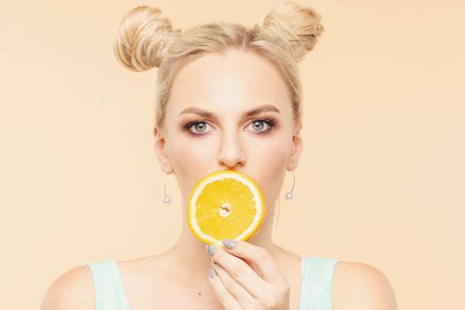 Pretty charming joyful attractive cheerful funny comic positive nude natural pure girl having two pieces of orange, closing one eye, isolated on beige background with copy space for advertisement