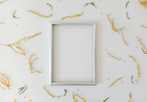 mockup with yellow mimosa flowers and blank photo frame with copy space. Spring, Easter concept.