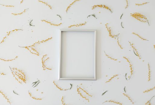 mockup with yellow mimosa flowers and blank photo frame with copy space. Spring, Easter concept.