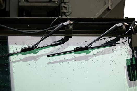 Wipers on the windshield of an armored car. Drops on the windshield armor glass. Windscreen of modern armored military truck.