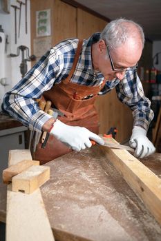 Carpenter filing a plank of wood in his Workshop. High quality photography.