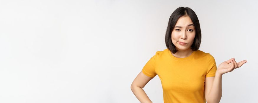 So what. Unbothered asian woman shrugging, looking clueless, standing against white background. Copy space