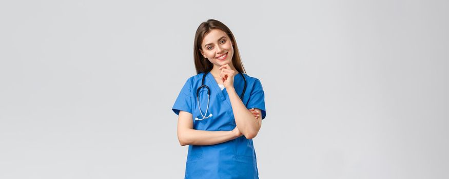 Medical workers, healthcare, covid-19 and vaccination concept. Upbeat smiling pretty nurse, doctor in blue scrubs, working clinic, looking with enthusiastic gaze camera, listening to coworker.