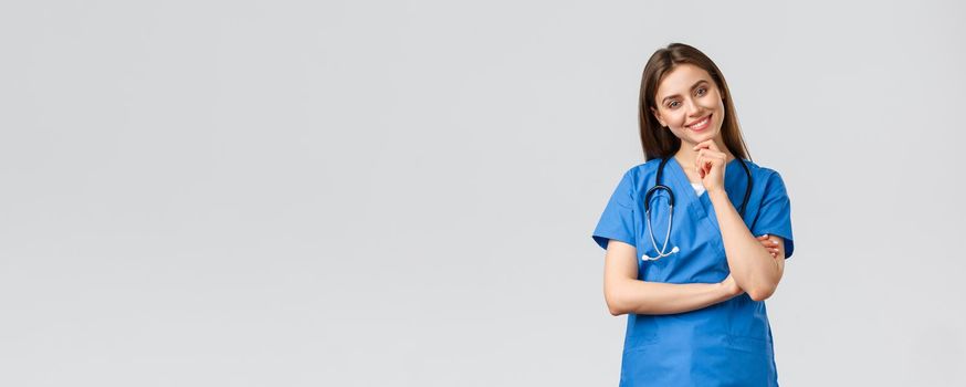 Medical workers, healthcare, covid-19 and vaccination concept. Upbeat smiling pretty nurse, doctor in blue scrubs, working clinic, looking with enthusiastic gaze camera, listening to coworker.