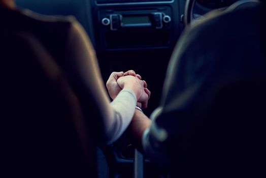 Rearview shot of a unrecognizable couple holding hands while driving in a car.