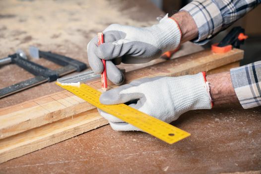 Woodwork and furniture making concept. Carpenter in the workshop marks out the details of the furniture cabinet using a setsquare, close up view. High quality photography