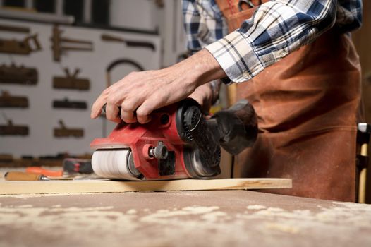 Carpenter sanding wood with belt sander at workshop in wooden board project or woodworking carpentry. High quality 4k footage