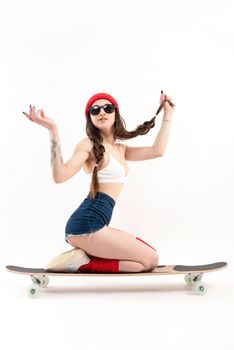 girl in a fashionable red hat, sitting on a longboard on a white background