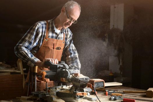 Carpenter using an electric circular saw, cutting a piece of wood. High quality photo.