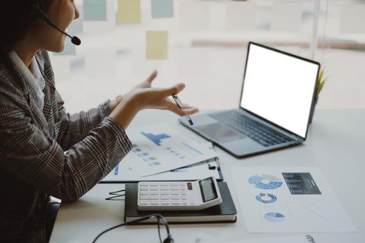 Business woman discuss with partners by video call. Female technical support agent trying to explain something to a client while working on laptop at call center