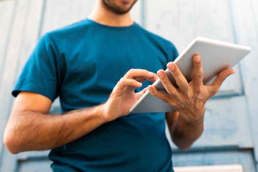 Unrecognizable caucasian man using digital tablet outdoors. Lifestyle and technology.