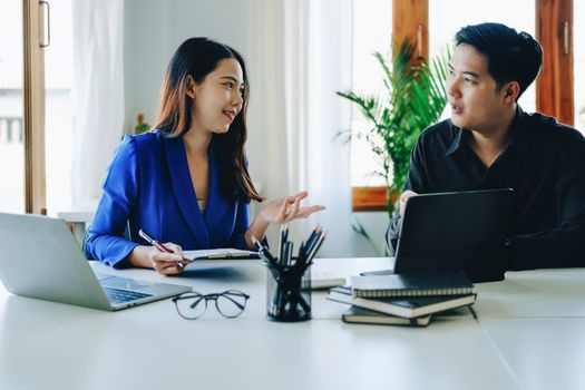 Concept of the impact of warring countries, male economists are using tablets to consult with marketing staff or accountants to adjust production and investment strategies to the current situation