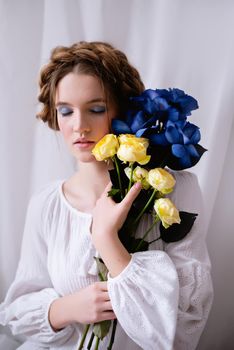 Caucasian Ukrainian woman in a white dress and flowers on white background . Symbol of the Ukrainian yellow blue colour. The calm lady is asleep. Concept - Stop War in Ukraine.