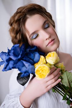 Portrait Caucasian Ukrainian girl in a white dress and flowers on white background . Symbol of the Ukrainian yellow blue colour. The calm lady is asleep. Concept - Stop War in Ukraine.