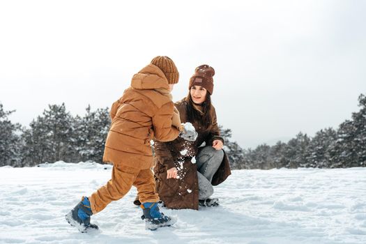 Woman with a little son on a winter hike in the snowy forest together