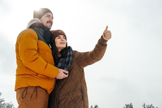 Young couple in love outdoor in snowy winter forest having a walk