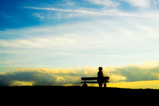 Silhouette of a woman sitting on a sunset hill. Shooting Location: Tokyo Chofu City