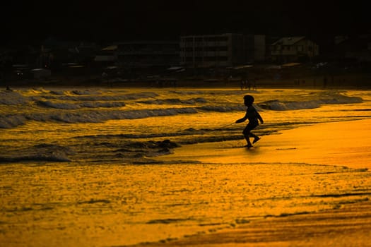 Kid playing at dusk waves. Shooting Location: Kamakura City, Kanagawa Prefecture