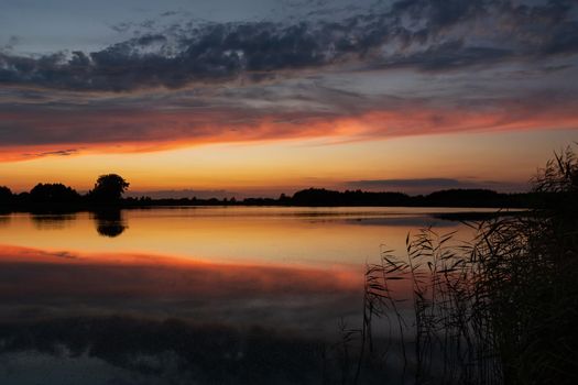 Reflection of clouds in the water after sunset, summer evening