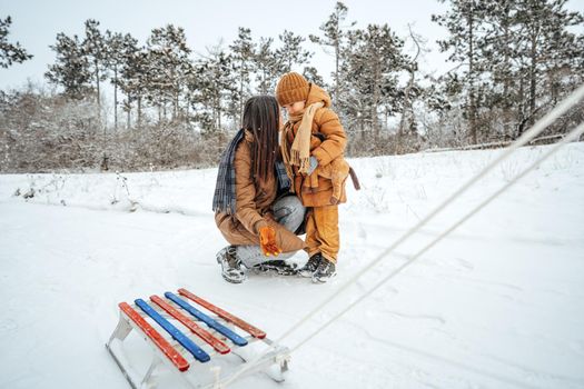 Woman with a little son on a winter hike in the snowy forest together