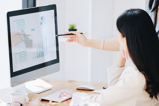 Consultation, Discussion, Marketing and Investment concept, female employee with pen is pointing at computer monitor to colleagues to draw conclusions and assess investment risks for the company