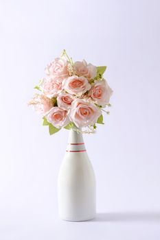 Bouquet of fresh pink flowers in a chic unlabelled white champagne bottle over green with copy space for Valentines Day