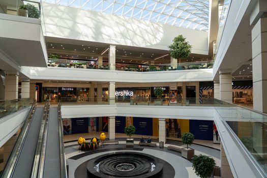 Grodno, Belarus - April 07, 2021: The interior of the modern large shopping and entertainment complex Trinity with a transparent glass roof.