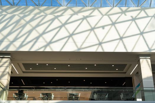 View on food court in a modern shopping mall with tratsparent glass roof. Food center in department store.