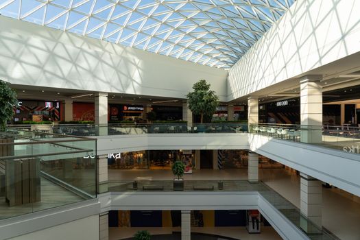 Grodno, Belarus - April 07, 2021: The interior of the modern large shopping and entertainment complex Trinity with a transparent glass roof.