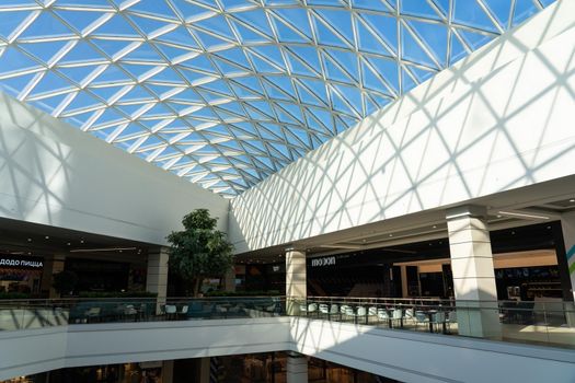 Grodno, Belarus - April 07, 2021: The interior of the modern large shopping and entertainment complex Trinity with a transparent glass roof.