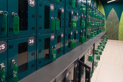 Cells for temporary storage of things in public place. Cells are green with metal locks. The cells are numbered with plastic numbers. Temporary storage of things.