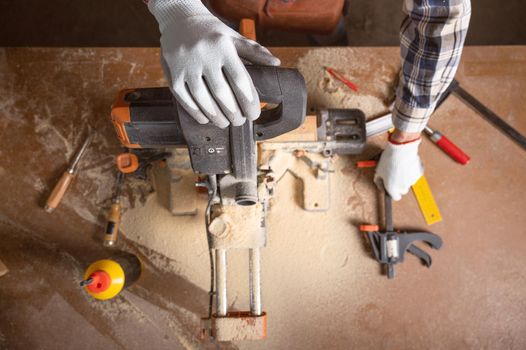Top view of carpenter holding plank near circular saw in carpentry shop. High quality photo.