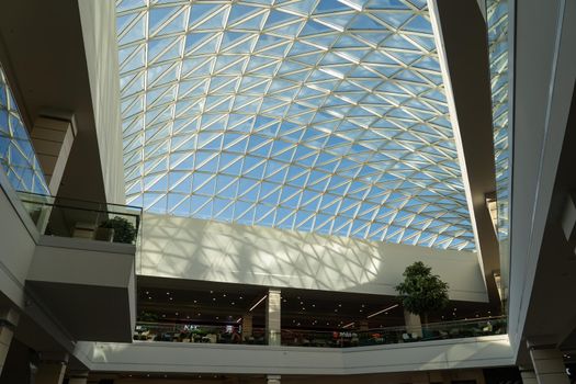 Grodno, Belarus - April 07, 2021: The interior of the modern large shopping and entertainment complex Trinity with a transparent glass roof.