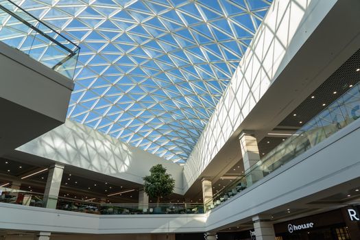 Grodno, Belarus - April 07, 2021: The interior of the modern large shopping and entertainment complex Trinity with a transparent glass roof.