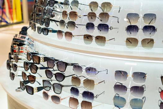 Sunglasses in the shop display shelves. Stand with glasses in the store of optics.