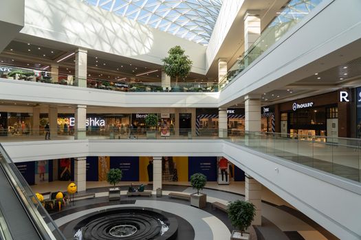 Grodno, Belarus - April 07, 2021: The interior of the modern large shopping and entertainment complex Trinity with a transparent glass roof.