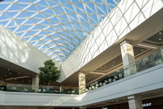 Grodno, Belarus - April 07, 2021: The interior of the modern large shopping and entertainment complex Trinity with a transparent glass roof.