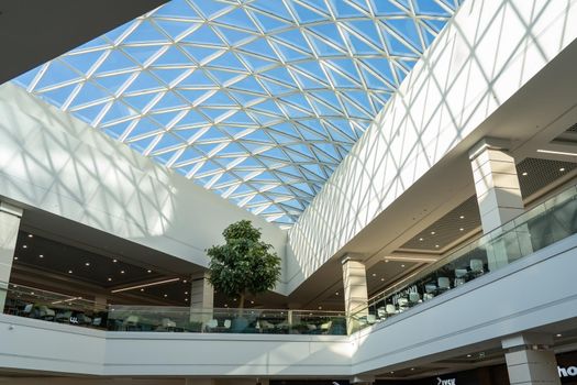 Grodno, Belarus - April 07, 2021: The interior of the modern large shopping and entertainment complex Trinity with a transparent glass roof.