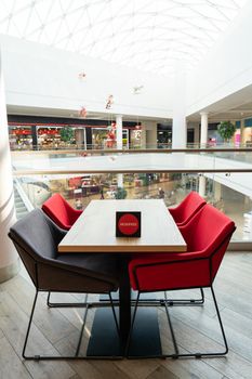 A table and soft chairs for visitors to the food court of a modern shopping center. The table is reserved.