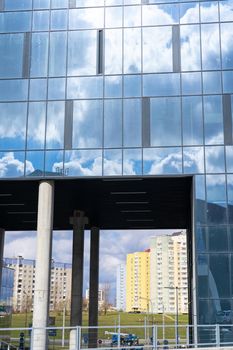 Architectural detail of the facade with multiple reflections of cloudy sky and the sun. Exterior of modern building.