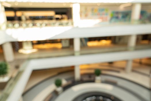 Blurred image interior of main hall shopping mall showing the floors and large skylight with natural light from glass roof. Glazed barrel vault spanning central axis, fashion boutique along corridor