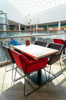 A table and soft chairs for visitors to the food court of a modern shopping center. The table is reserved.