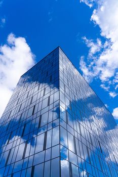 Architectural detail of the facade with multiple reflections of cloudy sky and the sun. Exterior of modern building. Architecture abstract background