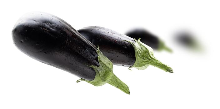 Ripe eggplants levitate on a white background.