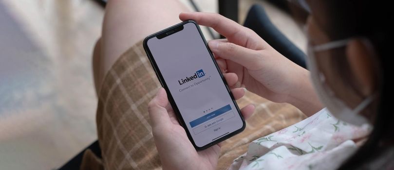CHIANG MAI, THAILAND, NOV 14 2021 : A women holds Apple iPhone Xs with LinkedIn application on the screen.LinkedIn is a photo-sharing app for smartphones..